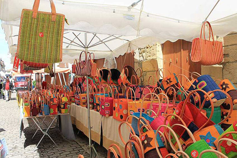 Market vendor displaying handcrafted leather bags and accessories at Villefranche market stall
